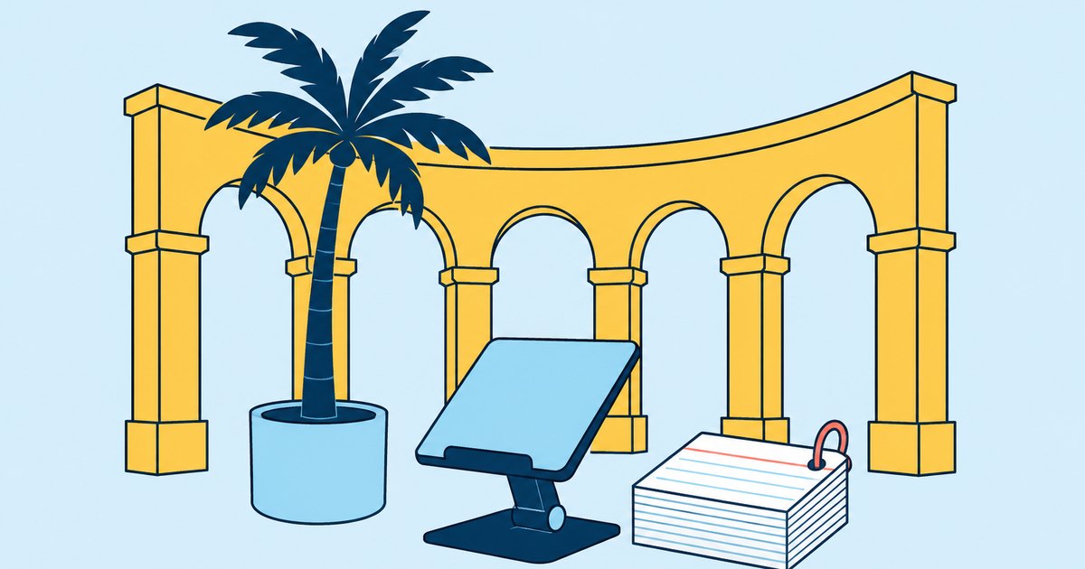 A sandstone arcade curves around a palm tree, laptop stand, and index card stack